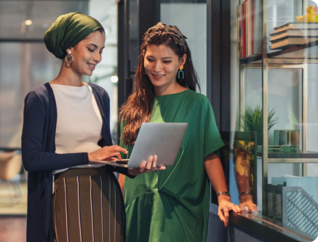 duas mulheres olhando para a imagem de um laptop